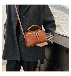 Detail of vintage brown leather bucket bag with metal zippers and sturdy top handle