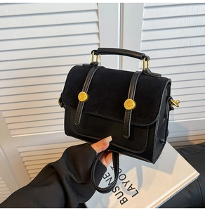 Detail of black vintage crossbody bag with suede patchwork and gold buckle closure