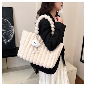 Detail of cream plush tote bag featuring vertical textures and soft ball handle