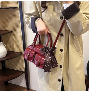 Model wearing a retro burgundy bowling bag with polished finish and decorative scarf