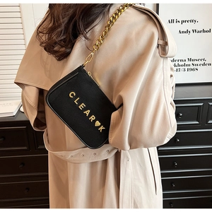 Close-up of black matte crossbody bag with gold chain and metal letter lettering