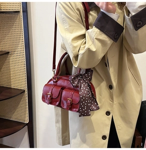 Detail of dark red vintage bowling bag with gold buckles and polka dot silk scarf