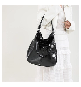 Gros plan d'un grand sac cabas en cuir verni noir avec clous argentés sur fond blanc