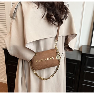 Brown frosted leather crossbody bag with gold chain worn over a beige trench coat