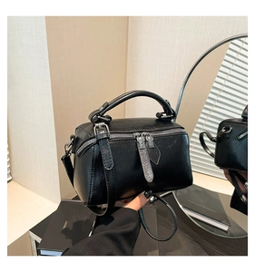 Detail view of black square crossbody bag with dual zippers and silver-tone hardware