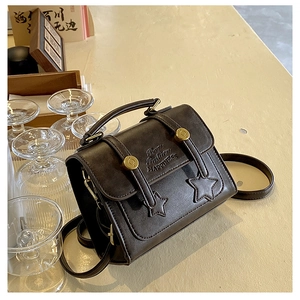 Close-up of vintage brown crossbody bag with star stitching and golden bead buckle