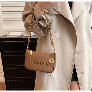 Detail of gold metal lettering and chunky chain on brown suede crossbody bag