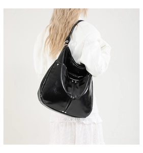 Détail d'un sac cabas en cuir verni noir avec rivets et anneaux métalliques