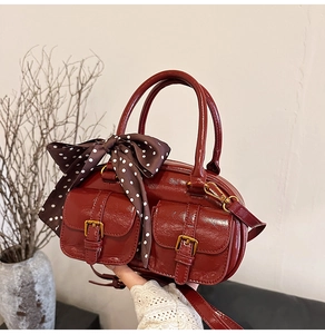 Detail of vintage burgundy bowling bag with gold buckles and polka dot silk scarf handle