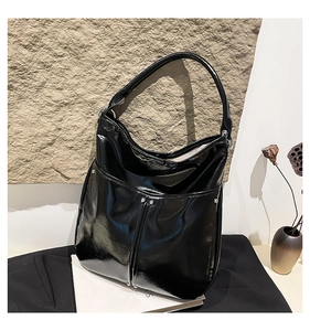 Détail du sac cabas noir brillant avec clous argentés et surpiqûres verticales chic