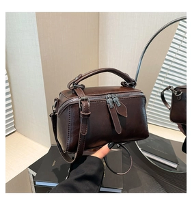 Detail of dark coffee box-shaped handbag with silver hardware and smooth double zippers