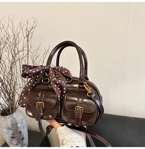 Detail of vintage brown glossy leather bowling bag with polka dot scarf and gold buckles