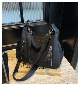 Details einer schwarzen Nylon-Tragetasche mit robustem Stoff und silbernen Reißverschlüssen