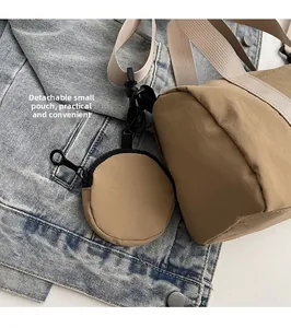 Détail du sac cylindrique en nylon kaki avec petite pochette ronde amovible sur denim