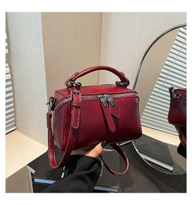 Close-up of vintage dark red leather satchel bag with silver hardware and top handle