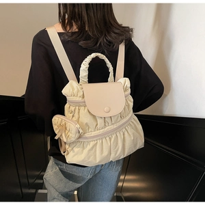Detailed view of cream ruffled fabric backpack with leather flap and mini bow charm