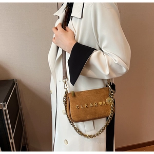 Close-up of brown matte suede small square bag with golden chain and metal logo detail
