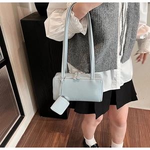 Dettaglio borsa a tracolla rettangolare azzurra con finitura liscia e mini astuccio