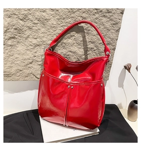 Détail du sac hobo en cuir verni rouge vif avec clous argentés et finition brillante