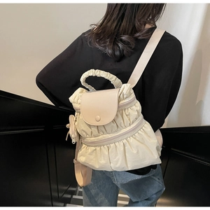 Detail of beige pleated nylon backpack with flap closure and round coin purse accessory
