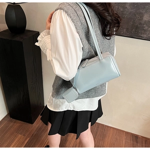 Borsa bowling azzurra con mini pochette accessoria indossata a spalla da una modella