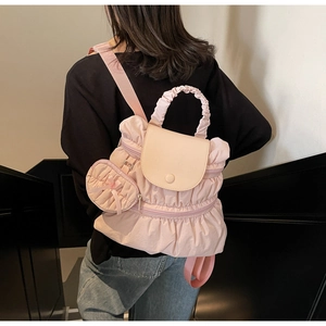 Close-up of light pink nylon backpack featuring ruffled layers and a mini bow charm
