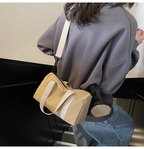 Détail du sac polochon en toile kaki avec sangles blanches et mini porte-monnaie