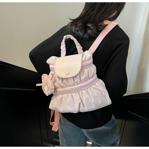 Detail of light pink pleated nylon backpack showing ruffle texture and coin pouch attachment