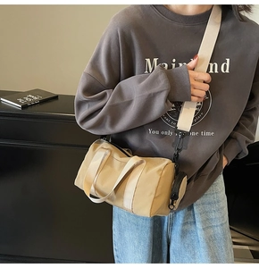 Détail du sac cylindrique kaki clair avec bandoulière large et pochette ronde amovible