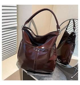 Détails de ce grand sac fourre-tout marron foncé brillant avec des rivets en métal