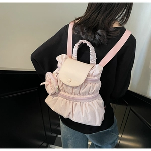 Detail of light pink pleated backpack with ruffled layers and a heart-shaped charm