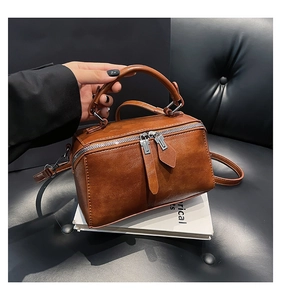 Detail of a brown vintage box bag with dual zippers and textured faux leather finish