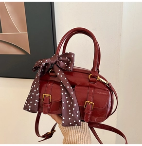 Close-up of vintage burgundy boston bag with glossy finish and silk scarf detail