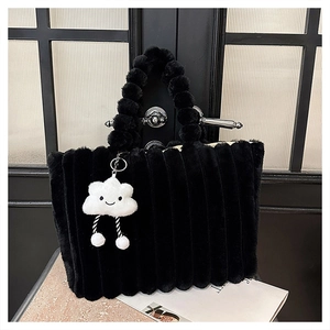 Detail of black faux fur tote bag with striped texture and plush ball handle