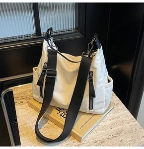 Detailansicht der weißen Canvas-Tasche mit schwarzen Riemen und Reißverschlüssen