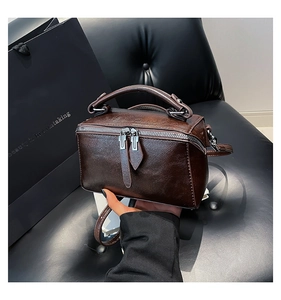 Macro view of dark brown oil wax leather handbag with double metal zipper closure