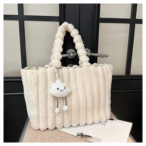 Detail of plush tote bag with vertical stripes, pom-pom handle and cloud charm