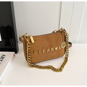 Detail of brown suede crossbody bag featuring gold metal CLEAR logo and chain strap