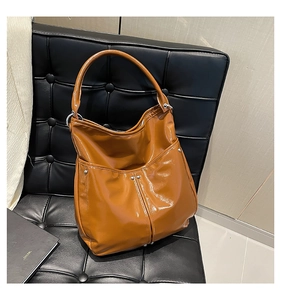 Détail du sac cabas caramel avec clous argentés sur texture cuir synthétique brillant