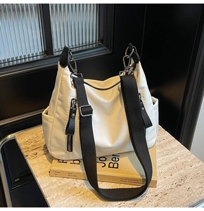 Detailansicht der cremeweißen Nylon-Hobo-Tasche mit Seitentasche und schwarzem Gurt