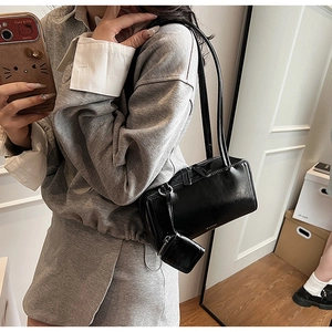 Dettaglio borsa a spalla in pelle nera con mini pochette e doppia cerniera lampo