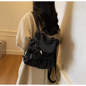 Back view of a stylish black pleated nylon backpack on a model with khaki coat