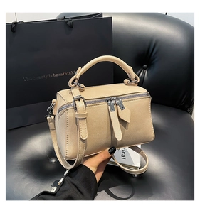Detailed view of beige faux leather bucket bag with thick handle and metal zipper
