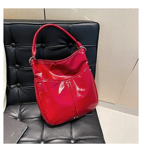 Gros plan du sac cabas en cuir verni rouge avec clous argentés sur un fauteuil noir