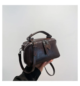 Detail view of dark brown faux leather bag featuring dual zipper and top handle