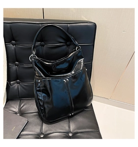 Détail du sac Hobo en cuir noir brillant avec des rivets argentés sur un siège