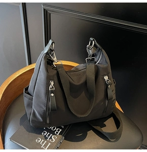 Detail der schwarzen Nylontasche mit zwei Reißverschlusstaschen und Silberbeschlägen