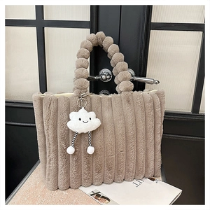Macro detail of khaki plush tote bag featuring fluffy ball handle and cloud charm