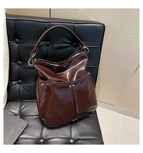 Détail d'un sac hobo marron foncé brillant avec des rivets argentés sur une chaise