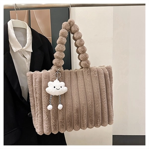 Detail of khaki plush tote bag featuring a fluffy ball handle and cloud charm